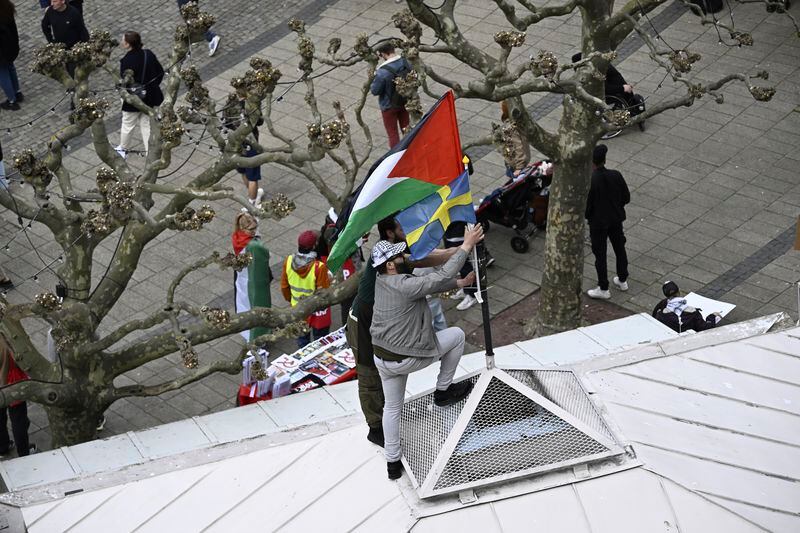 Protestors fix a Palestinian and Swedish flag atop of a building during a Stop Israel demonstration, between Stortorget and Mölleplatsen in Malmö, Sweden, Thursday, May 9, 2024. There have been calls for Israel to be excluded from the Eurovision Song contest because of its conduct in its war against Hamas. (Johan Nilsson/TT News Agency via AP)
