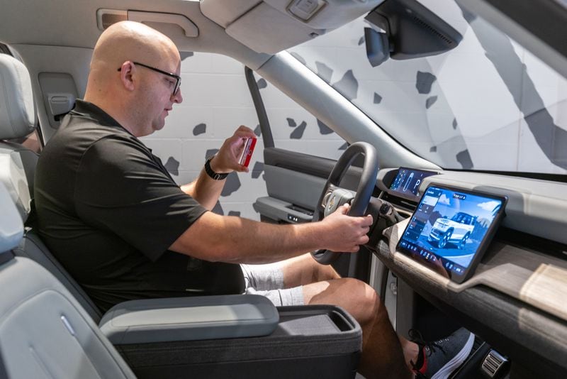 Jose Castillo sits in the new Rivian R2 prototype and records his experience at the Ponce City Market in Atlanta on April 27, 2024.  (Steve Schaefer / AJC)