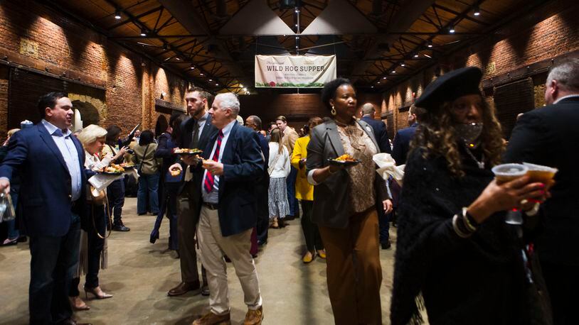 Attendees chat and carry plates of food to their seats during the annual Wild Hog Supper on Sunday, January 8, 2023, at the Georgia Railroad Freight Depot in Atlanta. State lawmakers and others gathered for the fundraiser which benefits the Georgia Food Bank. CHRISTINA MATACOTTA FOR THE ATLANTA JOURNAL-CONSTITUTION