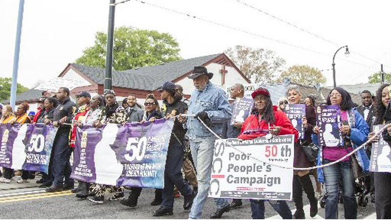 People march through the Martin Luther King Jr. Historic District during the March for Humanity in Monday. The march marks the 50th anniversary of Martin Luther King Jr.'s funeral procession through Atlanta. (REANN HUBER/REANN.HUBER@AJC.COM)