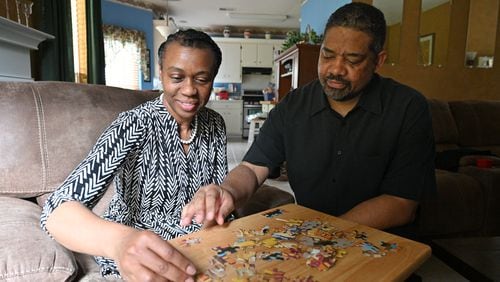 Robert Reid helps his wife Kim Reid, who was diagnosed with early-onset Alzheimer's, as she puts a puzzle together at their home in Hampton on Thursday, June 10, 2021. Hampton resident Robert Reid's wife, Kim, then 50, was diagnosed with early-onset Alzheimer's on June 15, 2017. (Hyosub Shin / Hyosub.Shin@ajc.com)