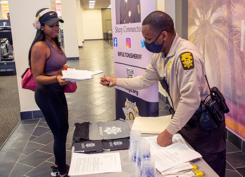 Santrez Fitter gives Kierston Hurst information at a Fulton County Sheriff's Office job fair at LA Fitness in Atlanta Friday, Feb. 11, 2022.   STEVE SCHAEFER FOR THE ATLANTA JOURNAL-CONSTITUTION