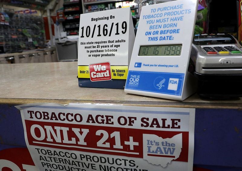 Signs on the counter at the Plum Food Mart in Springfield, Ohio inform customers that they must by 21-years-old to purchase tobacco and vaping products as of Wednesday, Oct. 16, 2019. In Georgia, the age limit is 18, and the medical community wants it raised to 21. BILL LACKEY/STAFF