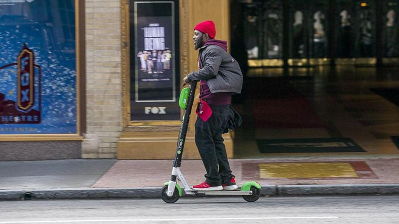 A man rides a Lime scooter in Midtown. (ALYSSA POINTER/ALYSSA.POINTER@AJC.COM)