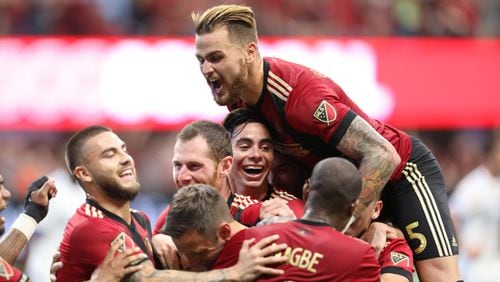 Atlanta United players embrace Atlanta United midfielder after scoring the third goal of the team.