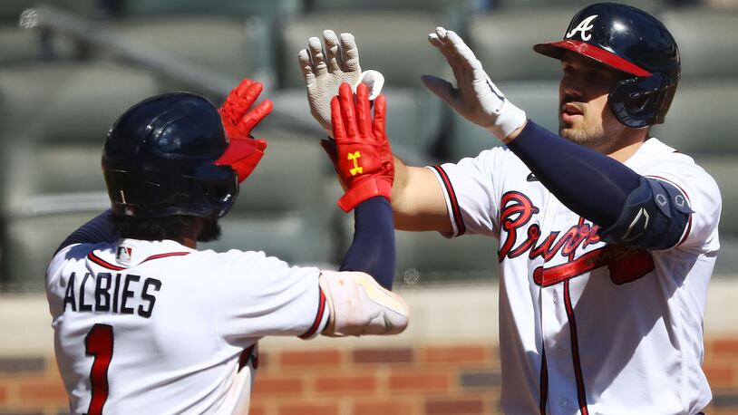 The Braves' Adam Duvall  is greeted by Ozzie Albies after hitting a two-run homer for a 5-0 lead over the Cincinnati Reds during the eighth inning of Game 2 of the National League wild card playoff series Thursday at Truist Park. (Curtis Compton / Curtis.Compton@ajc.com)