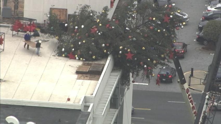 Crane buckles, leaving Christmas tree hanging off roof