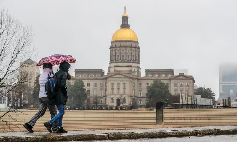 Zulheja Khariy (left) and Farima Khariy (right) walk along Martin Street in downtown Atlanta on Tuesday, Jan. 17, 2023 in a dreary wet day as the Georgia State Capitol looms in the background. (John Spink/The Atlanta Journal-Constitution)

