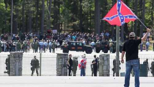One of a small group of "white power" activists waves a Confederate flag at the hundreds of counter-demonstrators at the Rock Stone Mountain rally in April 2016. Stone Mountain Park is bracing for another rally set for Saturday, Aug. 15, where several far-right militia groups and some white nationalist activists are expected to be confronted by a large coalition of counter-demonstrators. Ben Gray /AJC