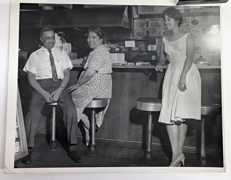 Amos Drugstore in Atlanta's West End was a mainstay of the neighborhood. It was also where Atlanta-born artist Emma Amos came of age. She is depicted here standing, next to her mother and father in 1960. The new Georgia Museum retrospective: "Emma Amos: Color Odyssey," opens Jan. 30, in Athens. Amos, born in Atlanta, used her career to challenge ideas around race, sex, and class. Emma Amos died in 2020 from complications of Alzheimer's disease.