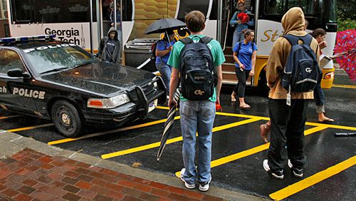 Students wait to board a Georgia Tech Stinger campus bus near police presence at Ferst Drive and Cherry Street. Students pay $85 a semester for transportation fees. The school has the highest amount of student fees of any public college or university in Georgia, at nearly $1,300 a semester. AJC FILE PHOTO.
