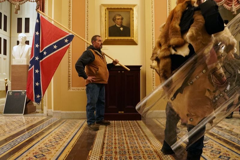 A man carries a Confederate flag inside the U.S. Capitol after it was stormed by supporters of President Donald Trump on Jan. 6. He was later identified as Kevin Seefried and arrested in Delaware along with his son, Hunter Seefried, who was also there that day. The FBI said Hunter bragged to a coworker about participating in the riot, according to The New York Times. (Erin Schaff/The New York Times)