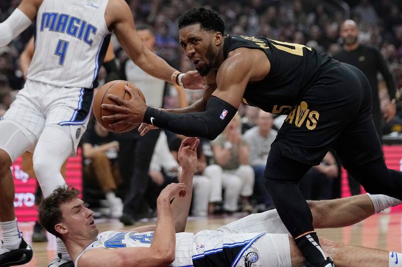 Orlando Magic forward Franz Wagner, bottom left, fouls Cleveland Cavaliers guard Donovan Mitchell, right, and falls to the floor in the first half of Game 7 of an NBA basketball first-round playoff series Sunday, May 5, 2024, in Cleveland. (AP Photo/Sue Ogrocki)