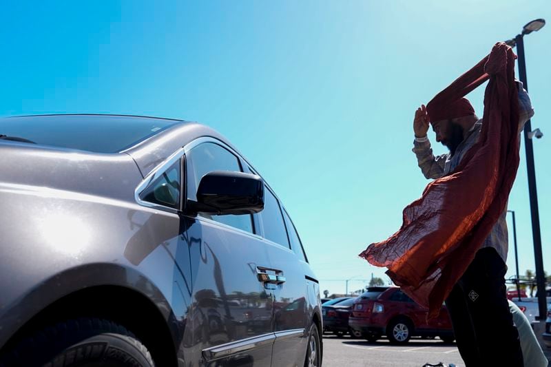 A migrant adjusts his headwear at a parking lot after being detained and processed for asylum by U.S authorities Tuesday, May 7, 2024, in San Diego. (AP Photo/Ryan Sun)