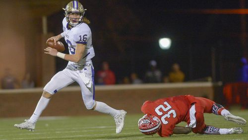 Cartersville quarterback Trevor Lawrence (16) avoids a tackle by Woodward Academy senior defensive end Terry Myrick during the second half of their GHSA quarterfinal game Friday, Nov. 26, 2016, in College Park. (Daniel Varnado/Special to AJC)