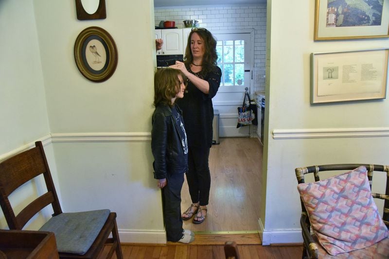 Children’s author Laurel Snyder takes her 10-year-old son Lewis’ height at their home in Ormewood Park recently. Her sons serve as inspiration, particularly for Snyder’s new book “Charlie & Mouse.” HYOSUB SHIN / HSHIN@AJC.COM