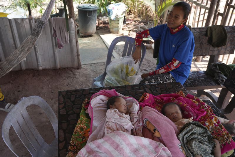 Kheang Pichphanith, 24, who is among the families relocated from Cambodia's archaeological site, sits next to her one-month-old twin babies at her home in Run Ta Ek village in Siem Reap province, Cambodia, on April 2, 2024. Cambodia's program to relocate people living on the famous Angkor archaeological site is drawing international concern over possible human rights abuses, while authorities maintain they're doing nothing more than protecting the UNESCO World Heritage Site from illegal squatters. (AP Photo/Heng Sinith)