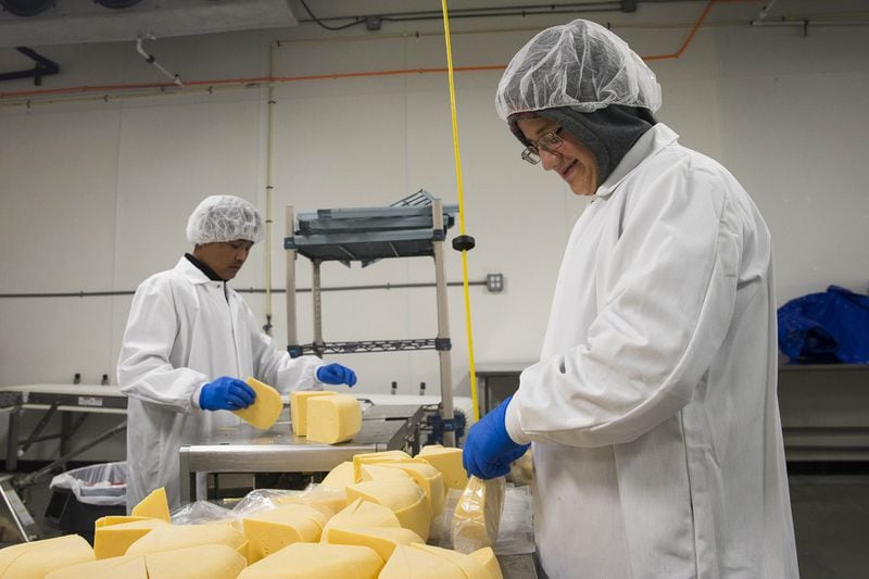 Production team member Mohammad Soda (right) packs sliced cheese at Gourmet Food International distribution center in Atlanta, where Amplio Recruiting helps place refugees. Mohammad is a refugee from Syria. ALYSSA POINTER/ALYSSA.POINTER@AJC.COM