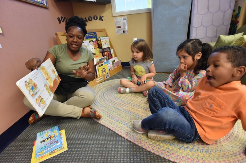 Ashton Aiken reads a book to (from left) Liliana Woods, 4, Carmen Castro, 3 and Eric Revell, 3, at Sheltering Arms International Village Center on Thursday, May 3, 2018. Sheltering Arms International Village Center is one of the few facilities where low-income parents can enjoy quality early childhood education through state subsidies. HYOSUB SHIN / HSHIN@AJC.COM