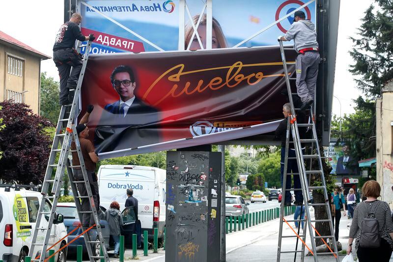 Workers remove an election poster of the incumbent President Stevo Pendarovski from a billboard, a day after the presidential and parliamentary elections, in Skopje, North Macedonia, on Thursday, May 9, 2024. North Macedonia elected its first woman president Wednesday as the governing Social Democrats suffered historic losses in twin presidential and parliamentary elections. (AP Photo/Boris Grdanoski)