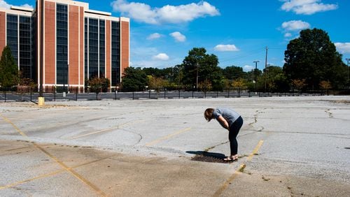 Hannah Palmer, Atlanta southside native, author and coordinator of the non-profit Finding the Flint, looks down the storm drain to see the water running at Virginia Crossings, in downtown East Point.