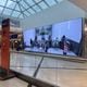 A video screen shows arriving passengers at the top of the escalators at at Hartsfield-Jackson International Airport.