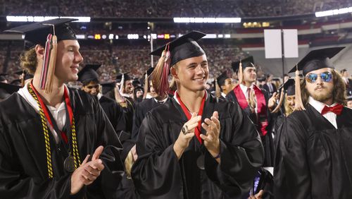 Georgia football player Ladd McConkey, center, reacts with fellow students of the C. Herman and Mary Virginia Terry College of Business as their degrees are conferred during undergraduate commencement ceremonies at Sanford Stadium this past May. McConkey, a star wide receiver, is successful off the field as well. He was named winner of the Wuerffel Trophy last week, which goes annually to the college football player considered most impactful when it comes community service. (Jason Getz / Jason.Getz@ajc.com)