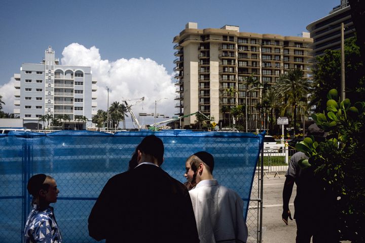 A family from Brooklyn near the site the then partially collapsed Champlain Towers South condo on Sunday, July 4, 2021, in Surfside, Fla. (Mark Abramson/The New York Times)