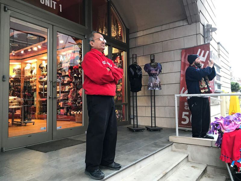 Abdul Karim stands outside of the Hello Atlanta souvenir shop where he works to watch the parade celebrating Atlanta United’s MLS Cup win. (TIA MITCHELL/TIA.MITCHELL@AJC.COM)