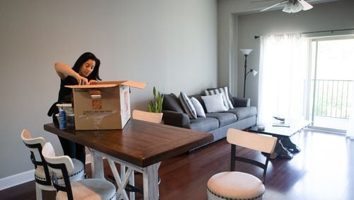 Michelle Enjoli unpacks a box at her apartment in Sandy Springs. Enjoli moved from a crowded area in Buckhead to a gated community in Sandy Springs after starting a business and transitioning to working at home full-time. (Christina Matacotta for The Atlanta Journal-Constitution)
