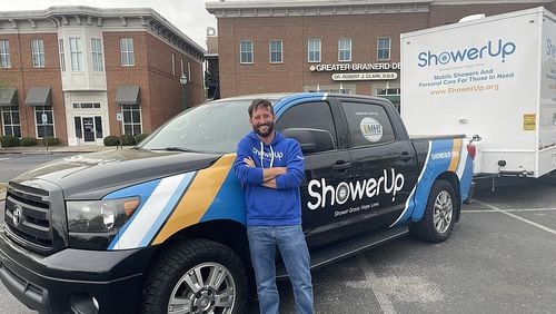 John Lynn, a ShowerUp volunteer, poses with a shower truck and trailer. Lynn is part of a nonprofit network that offers shower services to people living on the streets of Chattanooga, TN. (Photo Courtesy of Mark Kennedy)