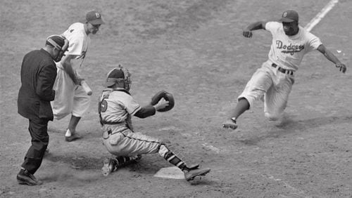 Brooklyn Dodgers’ Jackie Robinson steals home plate successfully as Boston Braves’ catcher Bill Salkeld is thrown off-balance on pitcher Bill Voiselle’s throw to the plate during the fifth inning of a Boston-Brooklyn game at Ebbets Field in New York on Aug. 22, 1948. Third baseman Billy Cox, who was at bat, watches Jackie slide. The umpire is Jocko Conlan. The Braves won 4-3. (AP Photo/Jack Harris)