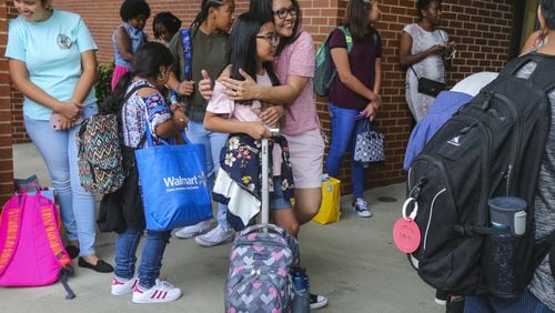 Myrna Gacusan gives 11-year old Rinna a hug before she begins her school day at Coleman Middle School in Duluth on August 7, 2017. The 1996 Summer Olympics in Atlanta triggered a population boom — and international immigrants — in the Atlanta area. With a school system that was already beginning to be considered among the best in the Southeast, Gwinnett County was a popular destination. JOHN SPINK/JSPINK@AJC.COM