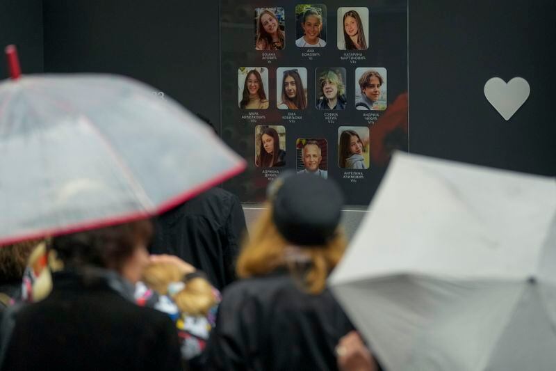 People gather in front of the Vladislav Ribnikar school during a memorial ceremony to mark the first anniversary of a shooting that killed 10 people in Belgrade, Serbia, Friday, May 3, 2024. (AP Photo/Darko Vojinovic)
