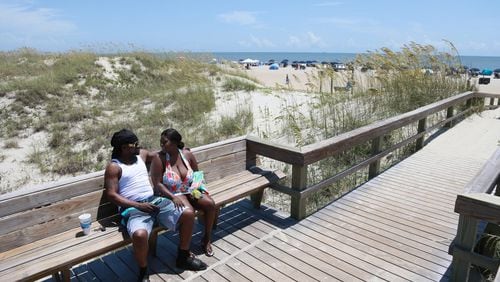 A couple sits on a bench at a beach crossover near the Tybee Island Pier.