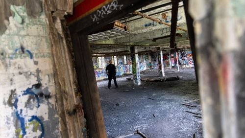 An officer walks through a building at the old prison farm during an Atlanta Police Department and Atlanta Fire Rescue media tour of the site for the proposed Atlanta Public Safety Training Center on Friday, May 26, 2023. (Arvin Temkar / arvin.temkar@ajc.com)