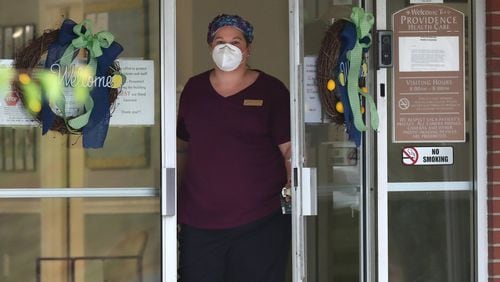 In this file photo, a healthcare worker on looks out the main doors at Providence of Sparta Health and Rehabilitation, where at least 38 patients and 11 staff members have been infected with coronavirus. (PHOTO by Curtis Compton ccompton@ajc.com)