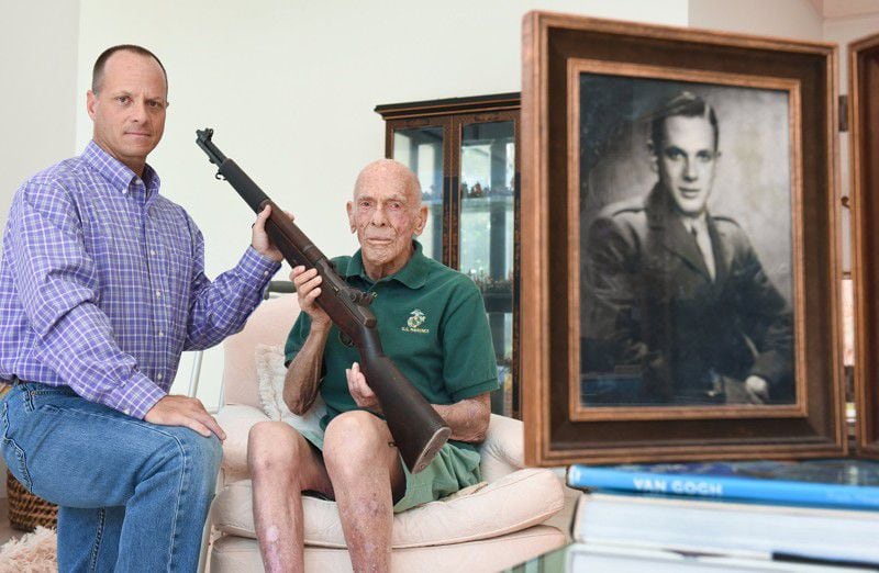 Richard Cowell, left, of Tequesta heard stories about his dad’s World War II rifle growing up in Palm Beach, where his dad Dick Cowell, 90, still lives. Richard Cowell, left, and his father Dick, with the rifle and his military portrait. (Photo: Melanie Bell / Palm Beach Daily News)