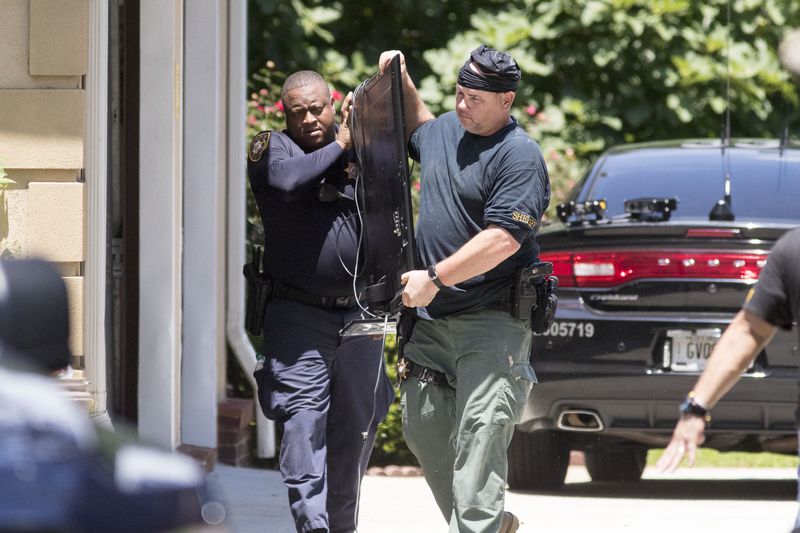Police officers remove items from a house at 1711 Five Forks Trickum Road that is involved in a multi-residential Gwinnett Metro Task Force raid. ALYSSA POINTER / ALYSSA.POINTER@AJC.COM