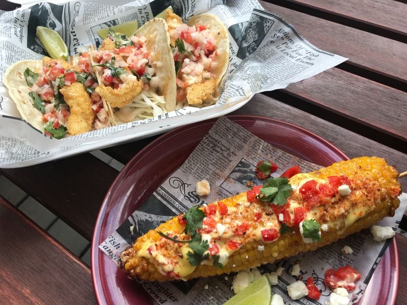 Southern Street Corn (foreground) is new to the Catfish Hox menu while the Tomahawk Tacos (background) remain a staple. The latter feature crunchy fried catfish fillets with pico de gallo and chipotle lime aioli on corn tortillas. They garnered top honors at the Taste of Marietta two years in a row. LIGAYA FIGUERAS / LIGAYA.FIGUERAS@AJC.COM