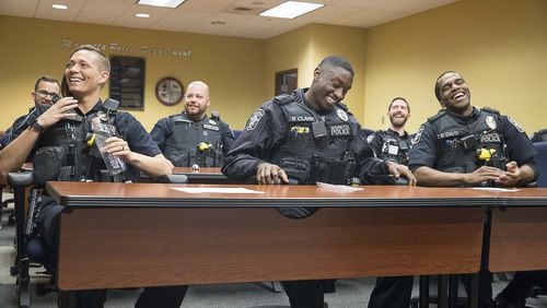 01/15/2019 — Marietta, Georgia — Marietta Police Officers Amelia Hines (front row, left) Rashad Clark (center) and D’Juan Davis (right) share a laugh during roll call for the evening shift at the Marietta Police Department, Wednesday, January 15, 2020. (ALYSSA POINTER/ALYSSA.POINTER@AJC.COM)