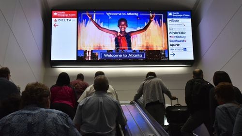 The new screen above the escalator leading to Hartsfield-Jackson’s domestic terminal shows a digital version of the Olympic old mural that used to hang in the space. It is now one of several rotating images. HYOSUB SHIN / HSHIN@AJC.COM