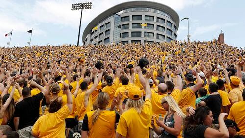In this Sept. 16, 2017, file photo, Iowa fans wave towards fans watching from University of Iowa's children's hospital at the end of the first quarter of an NCAA college football game against North Texas in Iowa City, Iowa. In the new tradition, known as The Wave, at the end of the first quarter fans in the 70,585-seat Kinnick Stadium turn to wave to the pediatric patients watching from the hospital, a 12-story building that overlooks the stadium from across the street. (AP Photo/Charlie Neibergall, File)