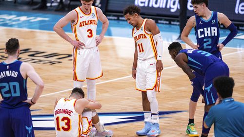 Atlanta Hawks guard Bogdan Bogdanovic (13) sits on the court after being fouled by Charlotte Hornets guard LaMelo Ball (2) during the first half of an NBA basketball game in Charlotte, N.C., Saturday, Jan. 9, 2021. (AP Photo/Jacob Kupferman)