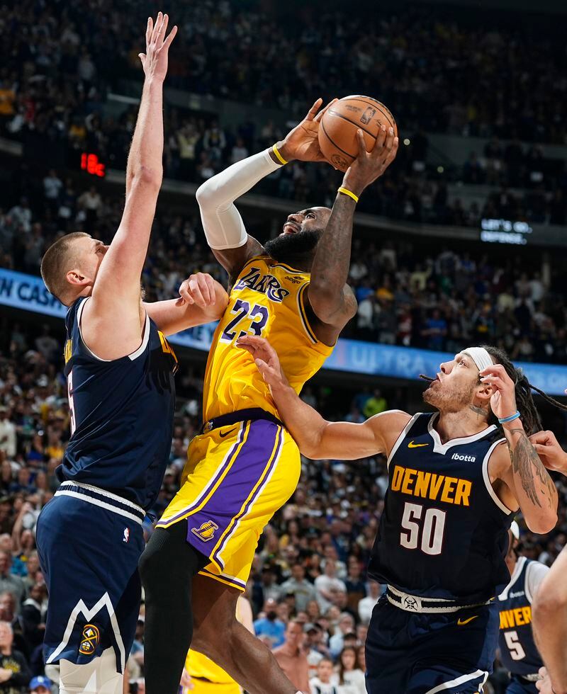 Los Angeles Lakers forward LeBron James (23) drives to the basket between Denver Nuggets center Nikola Jokic, left, and forward Aaron Gordon (50) in the second half of Game 5 of an NBA basketball first-round playoff series Monday, April 29, 2024, in Denver. (AP Photo/David Zalubowski)