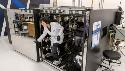 Dr. Qian Zhang, with Chemical Insights Research Institute, emerges from a 5-foot, 10-inch-tall, by 9-foot, 7-inch-long airtight chamber before sealing it. She and other scientists at the Marietta research facility were using the enclosure to test the ability of a newer-model 3D printer inside to capture pollutants with its built-in filtration unit, on March 26, 2024. She and other researchers have documented potentially harmful emissions from 3D printers without such filters, which are more common. (Steve Schaefer/steve.schaefer@ajc.com)