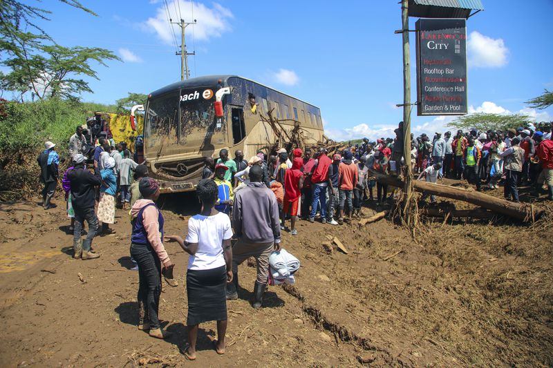 People gather around a bus that was swept away after a dam burst, in Kamuchiri Village Mai Mahiu, Nakuru County, Kenya, Monday, April 29, 2024. Police in Kenya say at least 40 people have died after a dam collapsed in the country's west. (AP Photo/Patrick Ngugi)