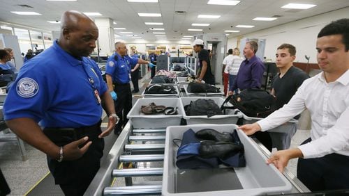 May 25, 2016 - Atlanta - TSA agent Darren Walker (left) helps passengers using the new system, where they slide their baggage onto the automated rollers. TSA unveiled new security "smart lanes" that have been installed in the South Security Checkpoint, which feature automated equipment that handles baggage. BOB ANDRES / BANDRES@AJC.COM