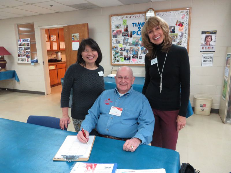 Jim Rogers, Tax-Aide client facilitator, gets ready to greet clients and help them fill out paperwork before meeting with the tax preparer. Rogers is pictured with Mary Louise Gilkenson, Crabapple Senior Center assistant, left, and Heidi Sowder, Crabapple Senior Center manager. (Photo by Laura Berrios)