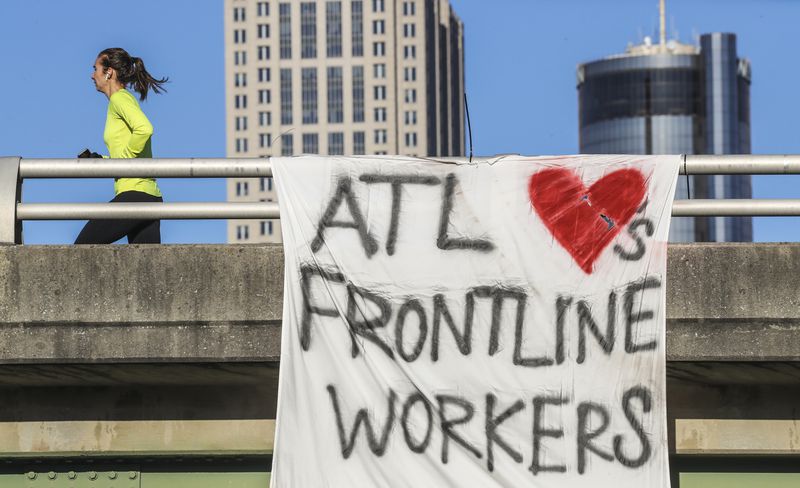 A banner offers praise to frontline workers in April 2020, during the early days of the COVID-19 crisis. The state is now facing another surge in cases, with nearly 90% of the state’s intensive care beds filled. JOHN SPINK/JSPINK@AJC.COM